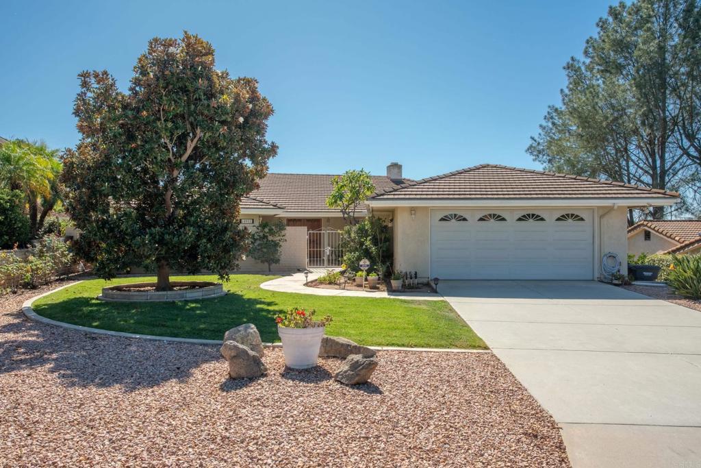 a front view of a house with a garden and trees