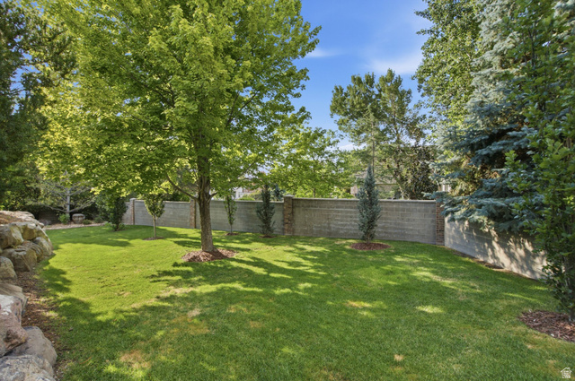 12308 Mariah Circle Draper, UT 84020 - Photo 250 of 293 Expansive grassy yard featuring a block retaining wall, mature shade trees, and layered landscaping