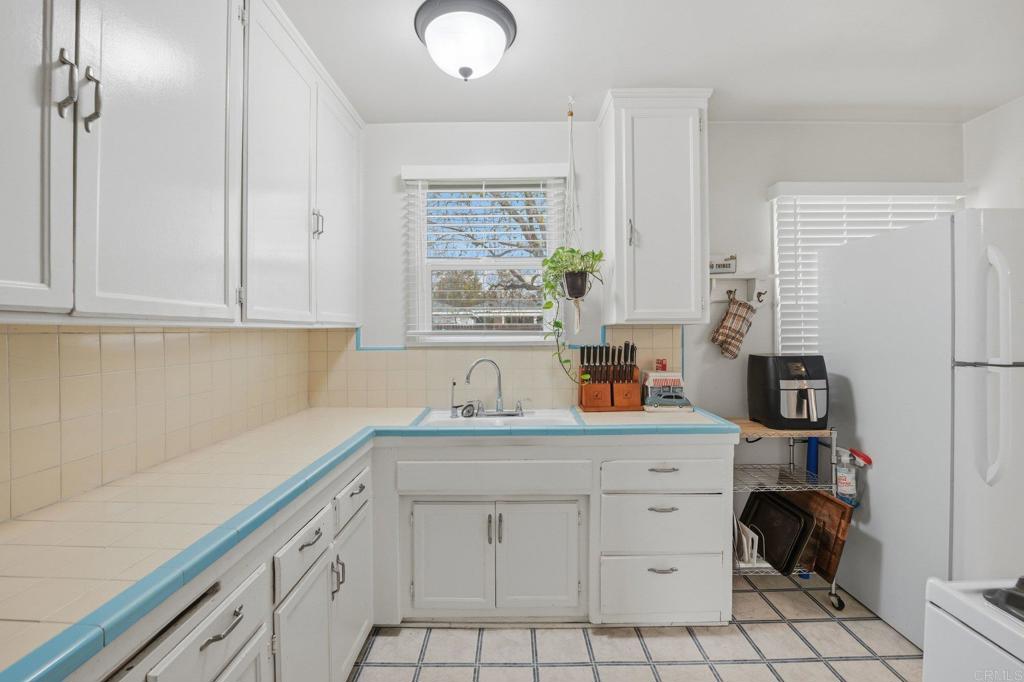 6974 Capistrano Way Riverside, CA 92504 - Photo 9 of 24 a kitchen with white cabinets a sink a window and appliances