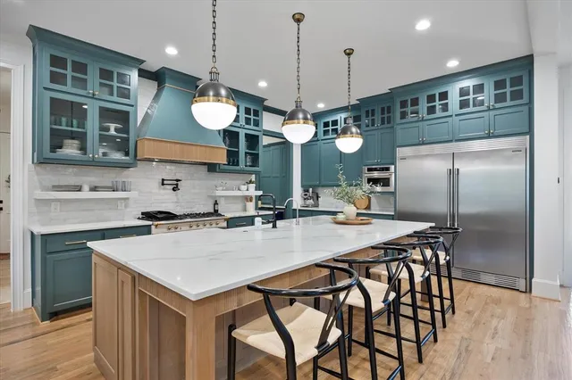 a kitchen with stainless steel appliances kitchen island granite countertop a stove a sink a dining table and chairs with wooden floor