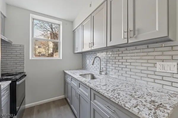 a kitchen with stainless steel appliances granite countertop a refrigerator a stove and a sink with wooden floor