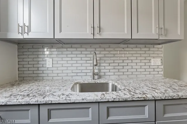 a kitchen with granite countertop a refrigerator and a sink