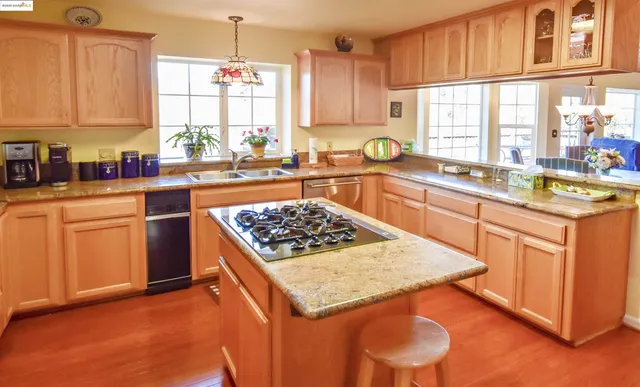a kitchen with a stove a sink wooden floor and a window