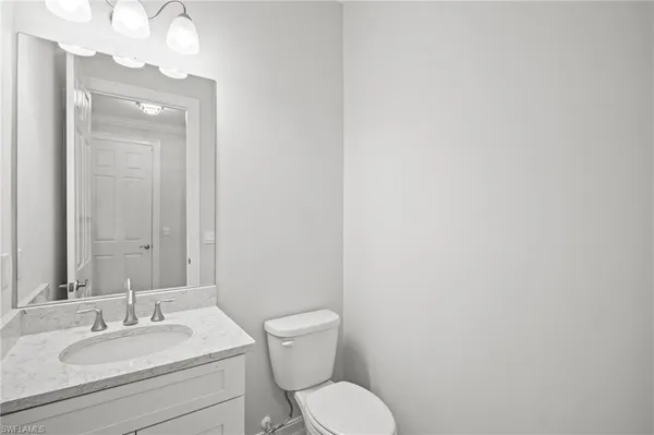 a bathroom with a granite countertop toilet a sink and mirror