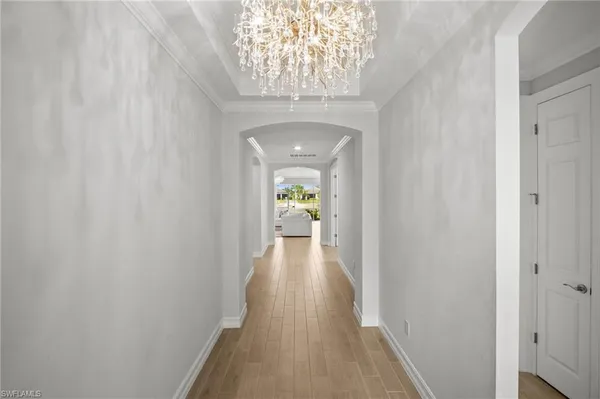 a view of a hallway with wooden floor and a chandelier