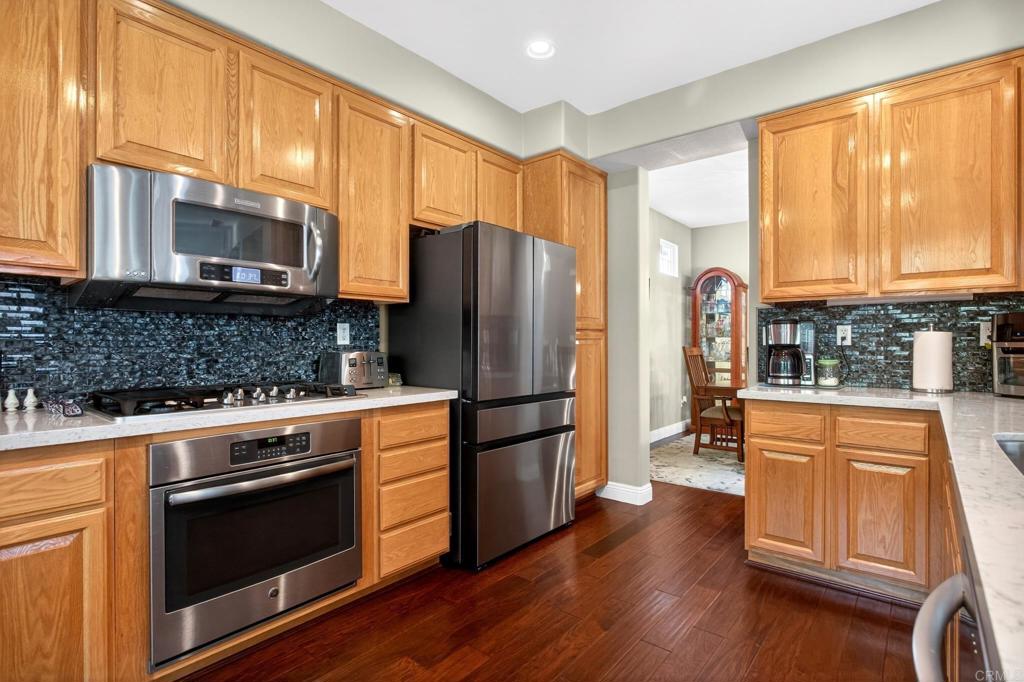 5531 Foxtail Loop Carlsbad, CA 92010 - Photo 18 of 62 a kitchen with granite countertop wooden floors stainless steel appliances and a window