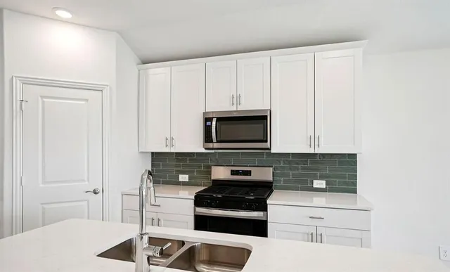 a kitchen with granite countertop white cabinets and stainless steel appliances
