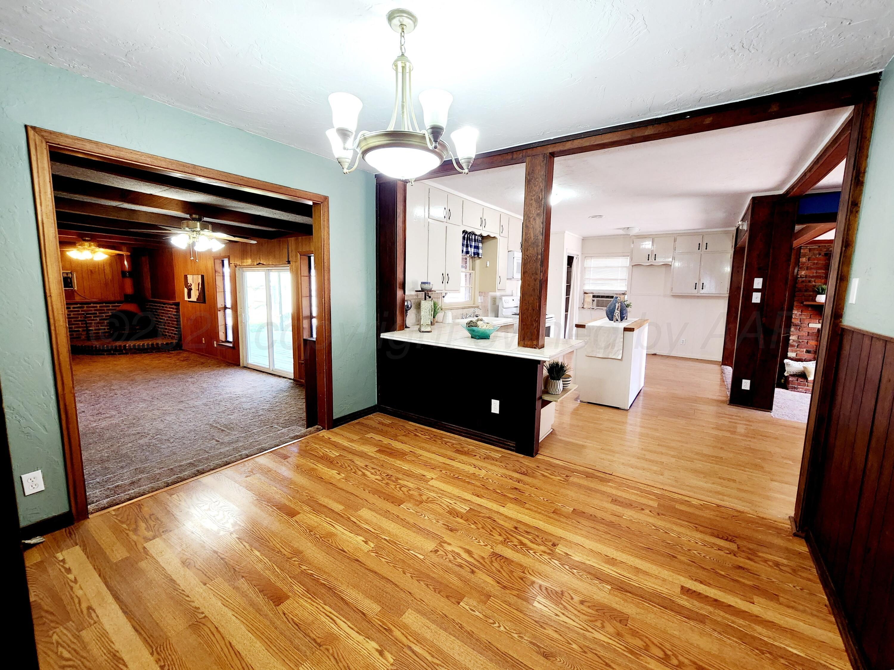 3320 Lynette Drive Amarillo, TX 79109 - Photo 7 of 19 a view of large hall with a dining table wooden floor and a kitchen view