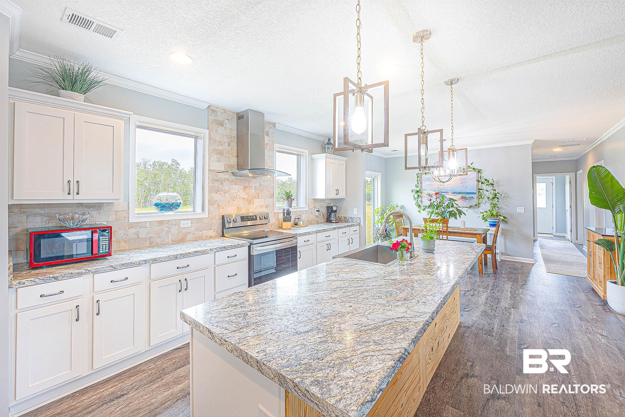 16000 John Bauer Road Summerdale, AL 36580 - Photo 14 of 34 Kitchen featuring white cabinetry, a sink, an island with sink, stainless steel range with electric stovetop, and wall chimney exhaust hood