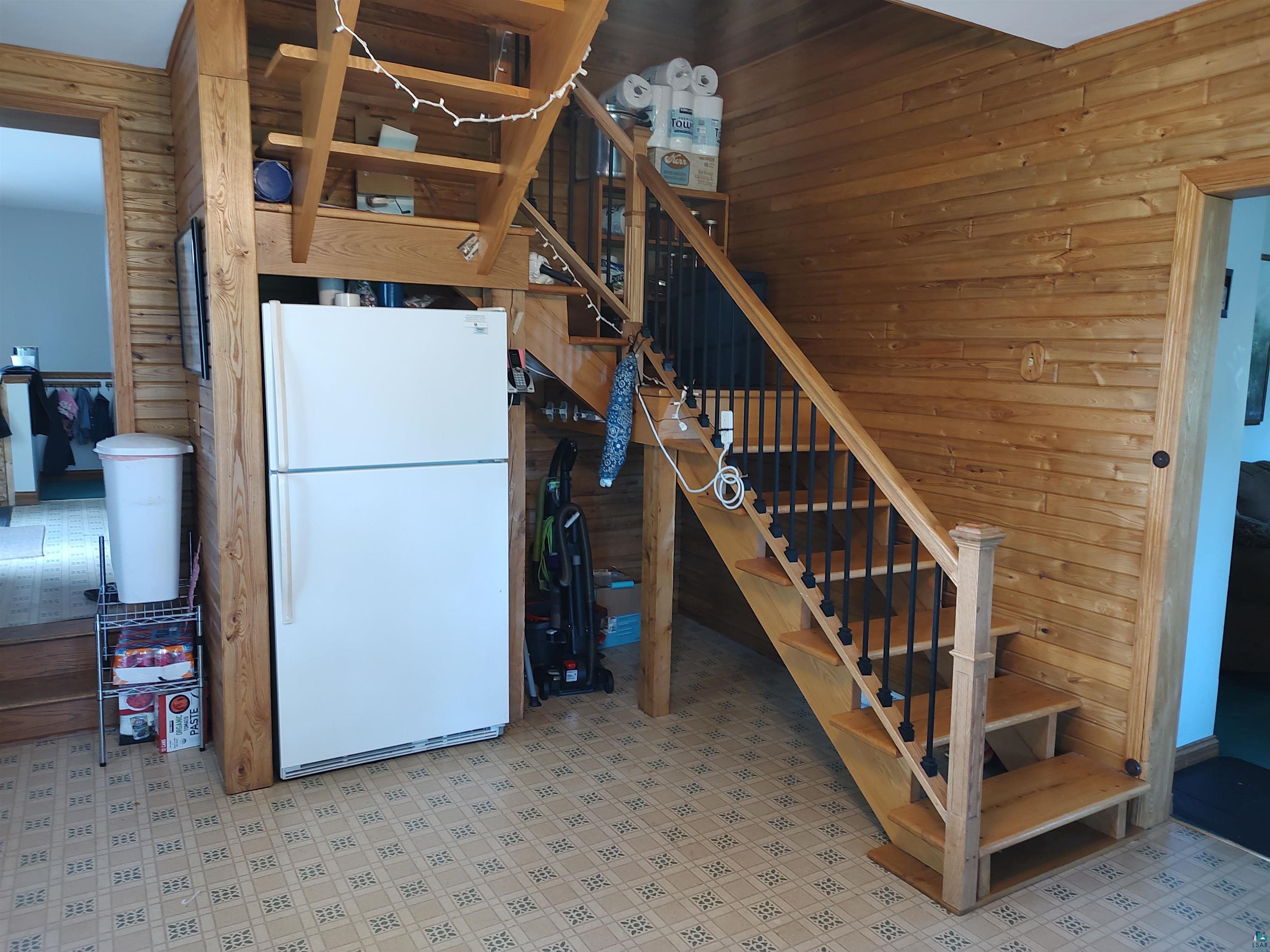 2585 Hautala Road Iron River, WI 54847 - Photo 5 of 28 Wood-finish wall paneling, open staircase with black metal balusters, integrated under-stair storage shelving, and patterned linoleum flooring