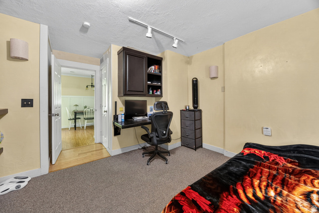 730 East 200 North Logan, UT 84321 - Photo 11 of 28 Carpeted room featuring a built-in dark wood desk with shelving, track lighting, and a doorway opening to a room with wood flooring and wainscoting