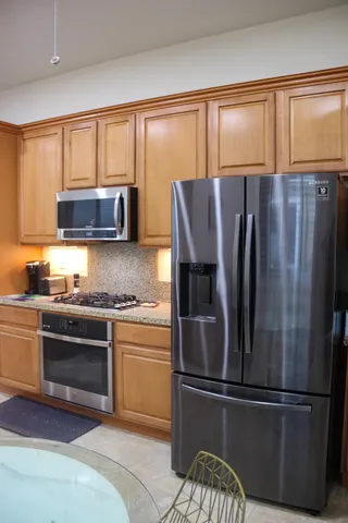 a kitchen with stainless steel appliances granite countertop a refrigerator and a stove top oven