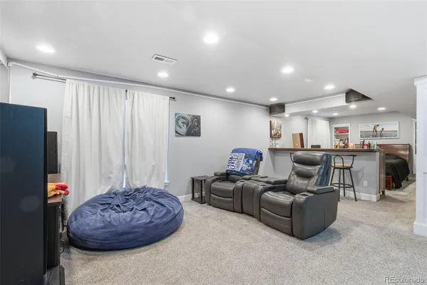 a living room with furniture and a refrigerator
