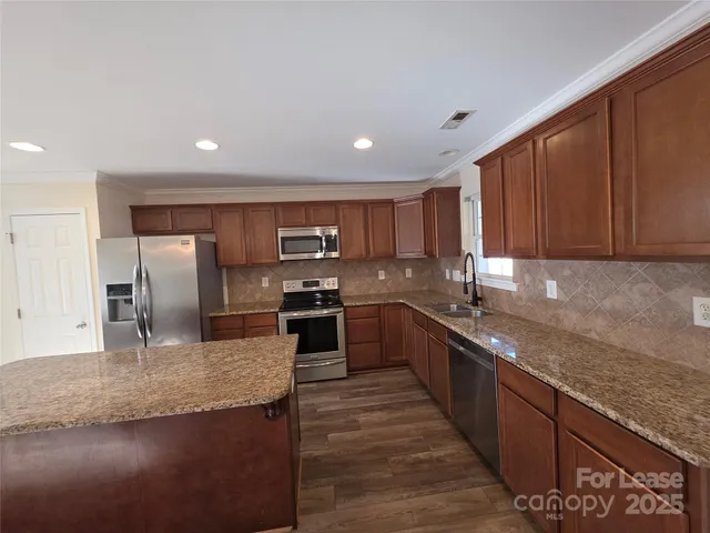 a large kitchen with granite countertop a large counter top stainless steel appliances and cabinets