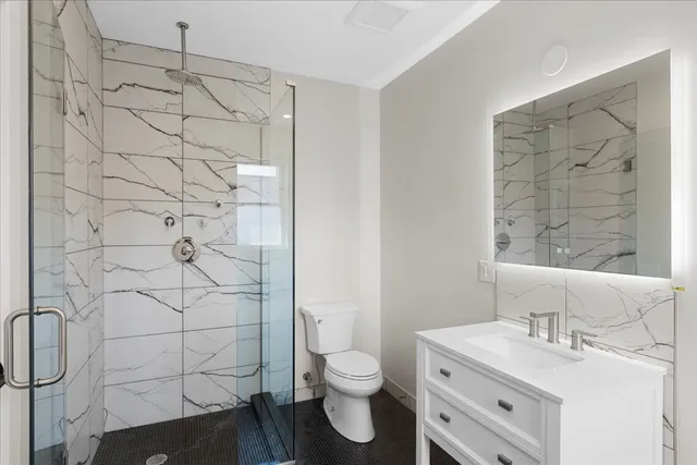 a bathroom with a granite countertop sink toilet and shower
