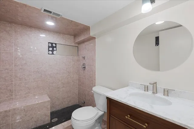 a bathroom with a granite countertop toilet a sink a mirror and vanity