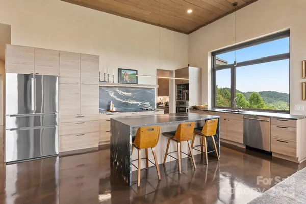 a kitchen with stainless steel appliances granite countertop a table chairs and a refrigerator