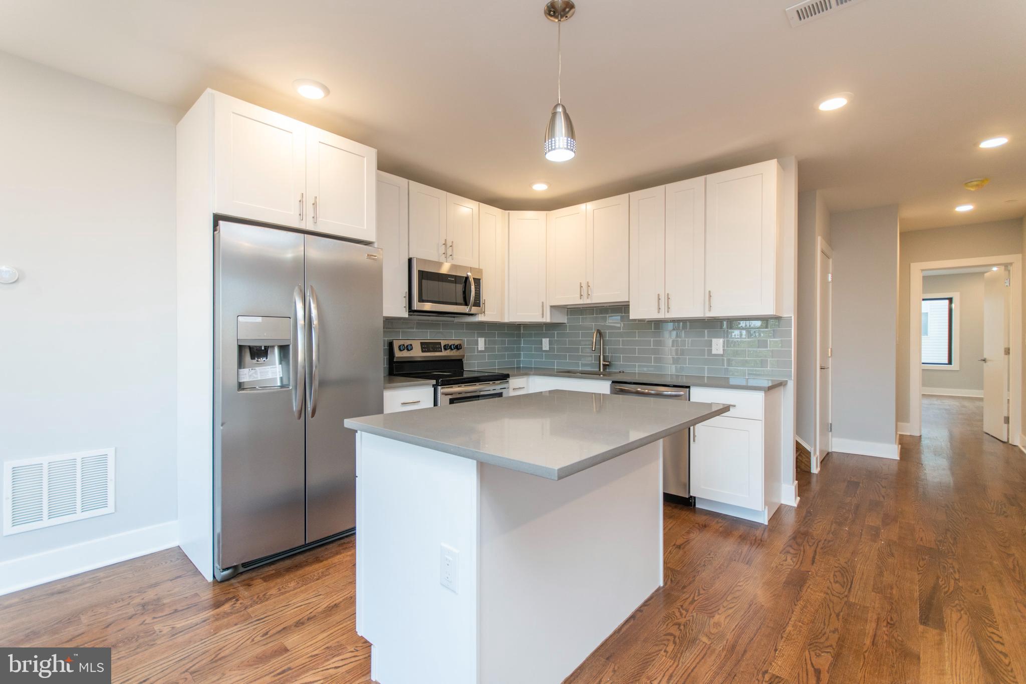 812 North Uber Street, Unit 6 Philadelphia, PA 19130 - Photo 3 of 25 a kitchen with kitchen island stainless steel appliances a sink cabinets and wooden floor