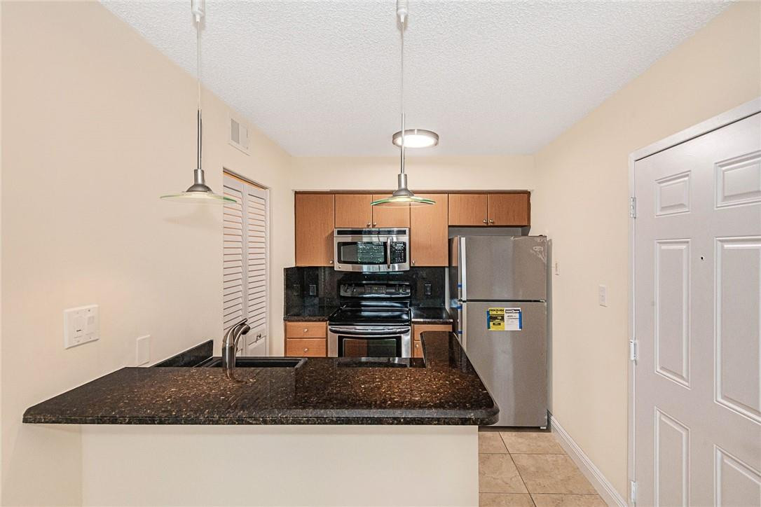 620 South Park Road, Unit 213 Hollywood, FL 33021 - Photo 4 of 28 a kitchen with kitchen island a counter top space a sink and refrigerator