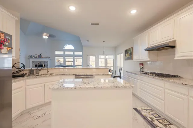 a kitchen with granite countertop a sink stove and cabinets