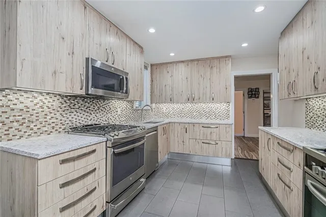 a kitchen with granite countertop a sink cabinets and stainless steel appliances