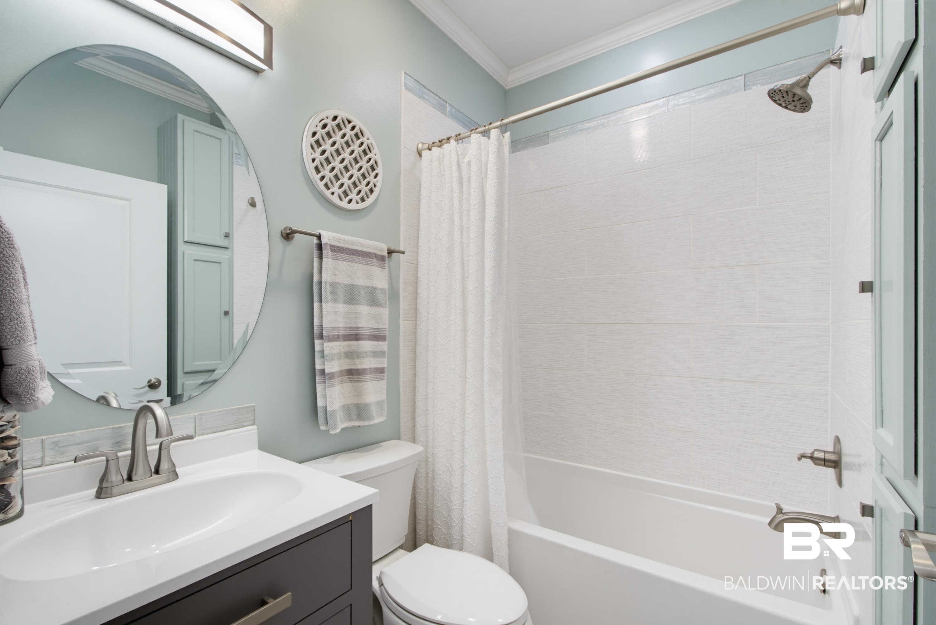 7472 Coopers Landing Road Foley, AL 36535 - Photo 19 of 40 Bathroom featuring a dark wood-finish vanity with an integrated sink, brushed nickel hardware, and a circular mirror