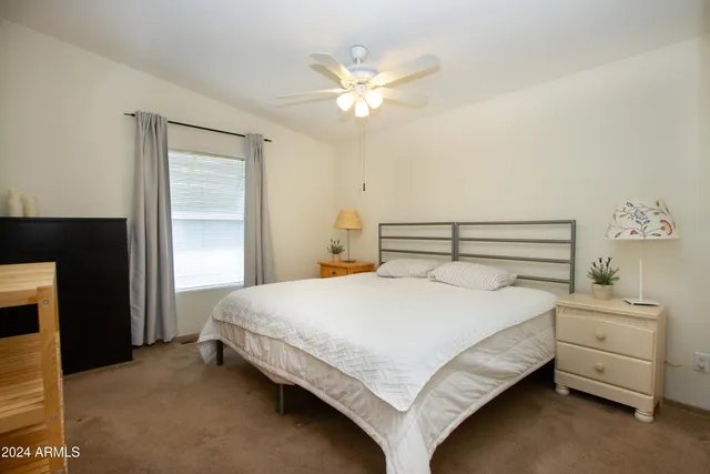 a bedroom with a bed and a flat tv screen on dresser