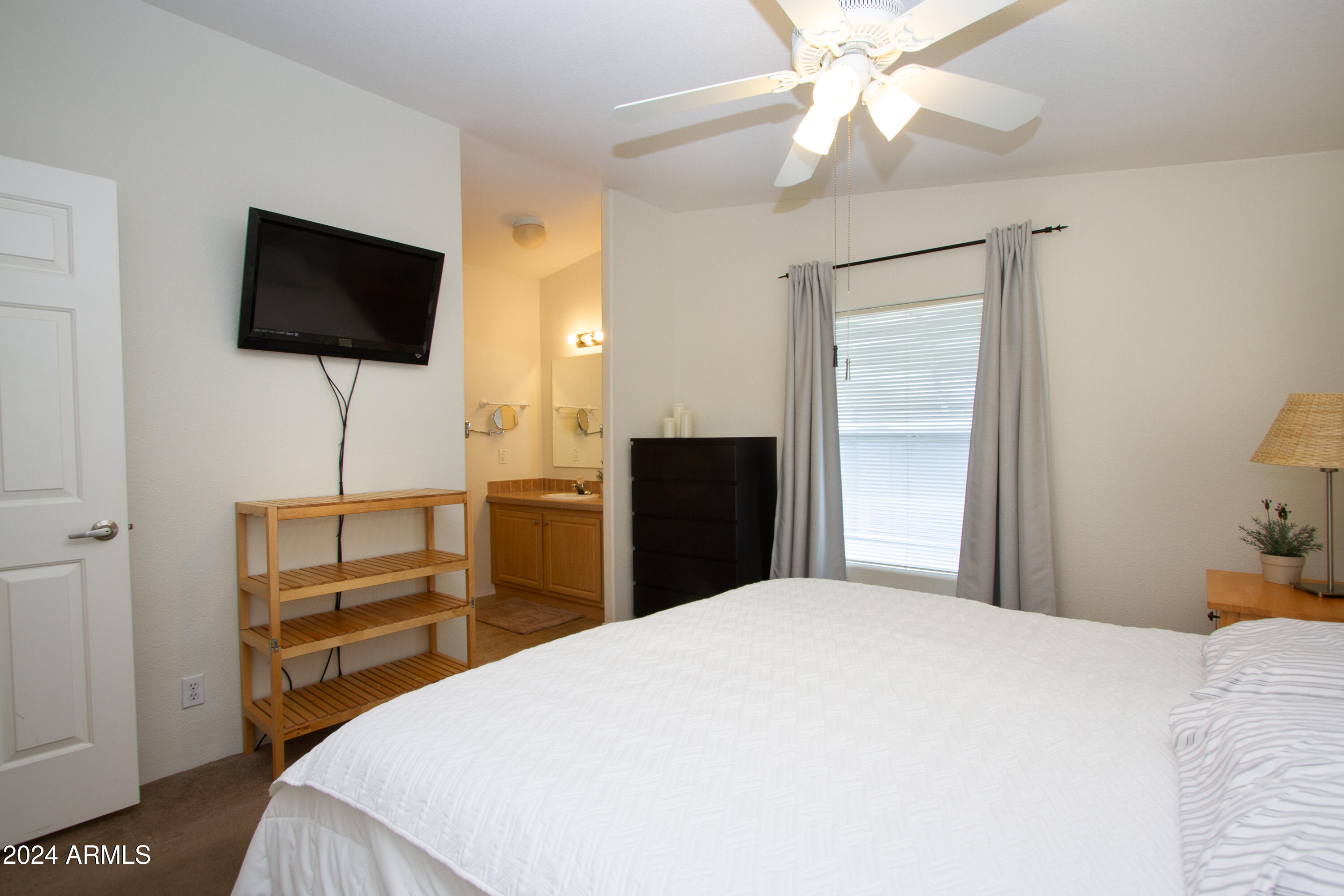 3700 South Tomahawk Road, Unit 93 Apache Junction, AZ 85119 - Photo 25 of 40 a bedroom with a bed and a flat tv screen on dresser