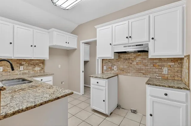 a kitchen with white cabinets and appliances