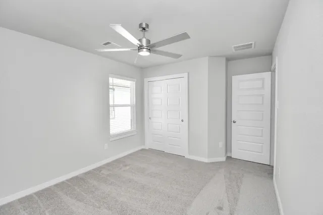 an empty room with closet and fan