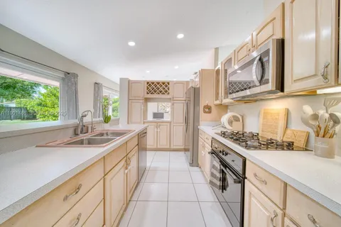 a kitchen with stainless steel appliances granite countertop a sink and a stove next to a window