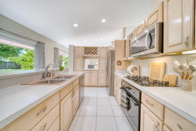 a kitchen with stainless steel appliances granite countertop a sink and a stove next to a window
