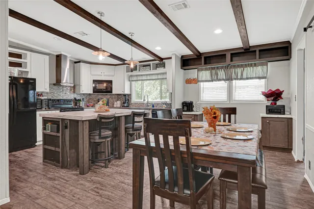 a kitchen with stainless steel appliances kitchen island granite countertop a table chairs and a refrigerator