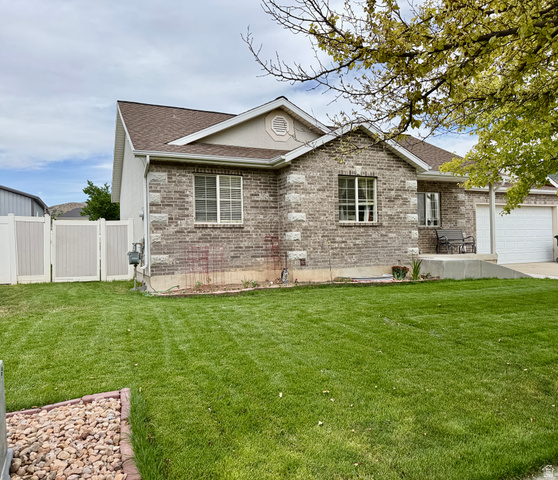 1353 360 West Payson, UT 84651 - Photo 3 of 16 Brick and siding exterior featuring a covered front porch, white garage door, and a private side yard with a white vinyl fence and double gate