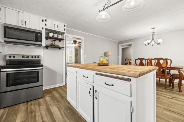 a kitchen with kitchen island granite countertop a stove top oven a sink dishwasher a dining table and chairs with wooden floor