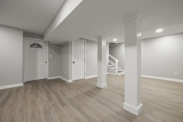 a view of an empty room with wooden floor and staircase