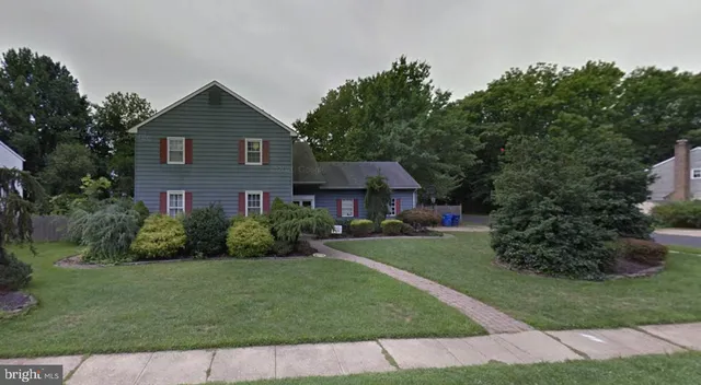 a view of a brick house next to a yard with plants and trees