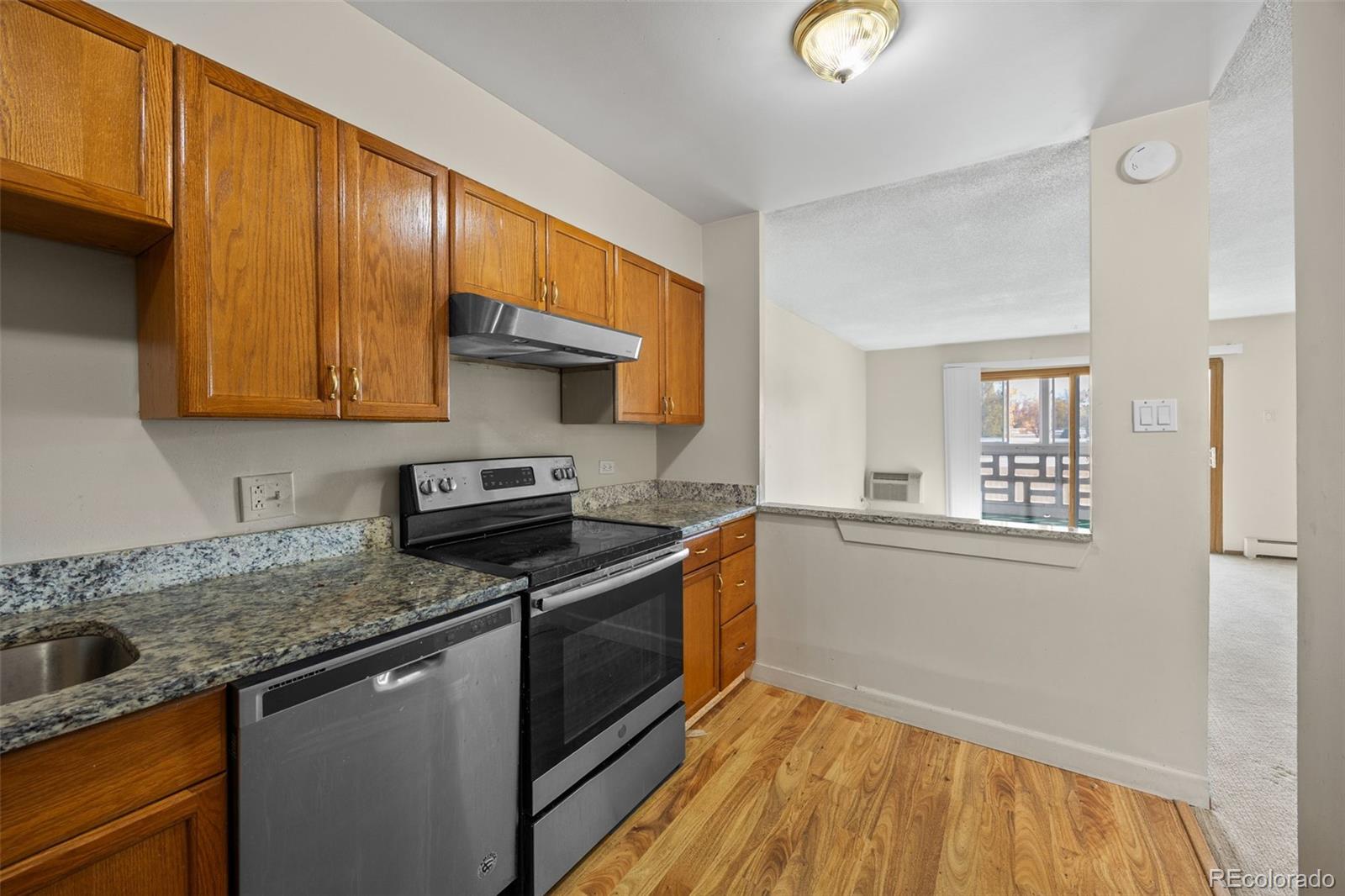 650 South Alton Way, Unit 3B Denver, CO 80247 - Photo 7 of 19 a kitchen with granite countertop wooden cabinets stainless steel appliances and a counter space