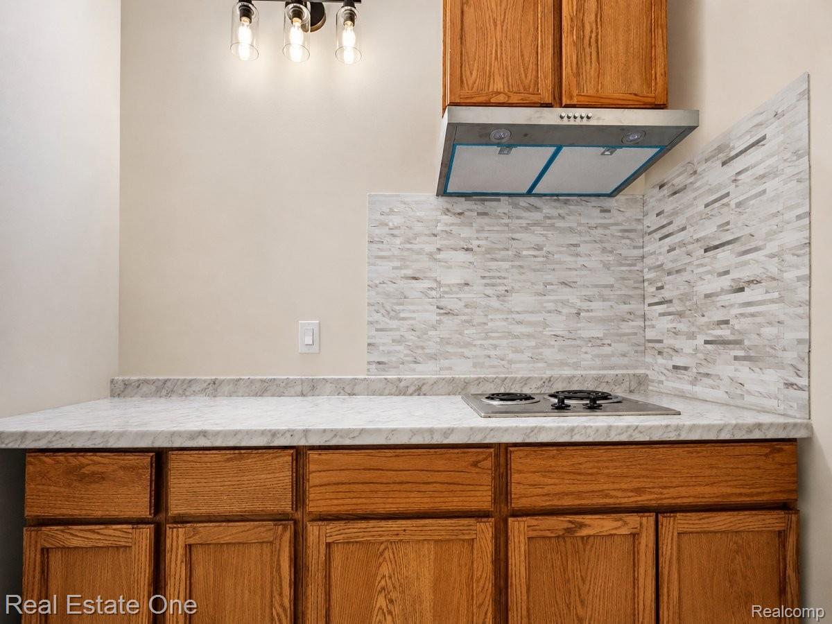 3465 Everett Drive Rochester, MI 48307 - Photo 17 of 69 Kitchenette featuring wood cabinetry, a white stone-look countertop, and a built-in electric cooktop