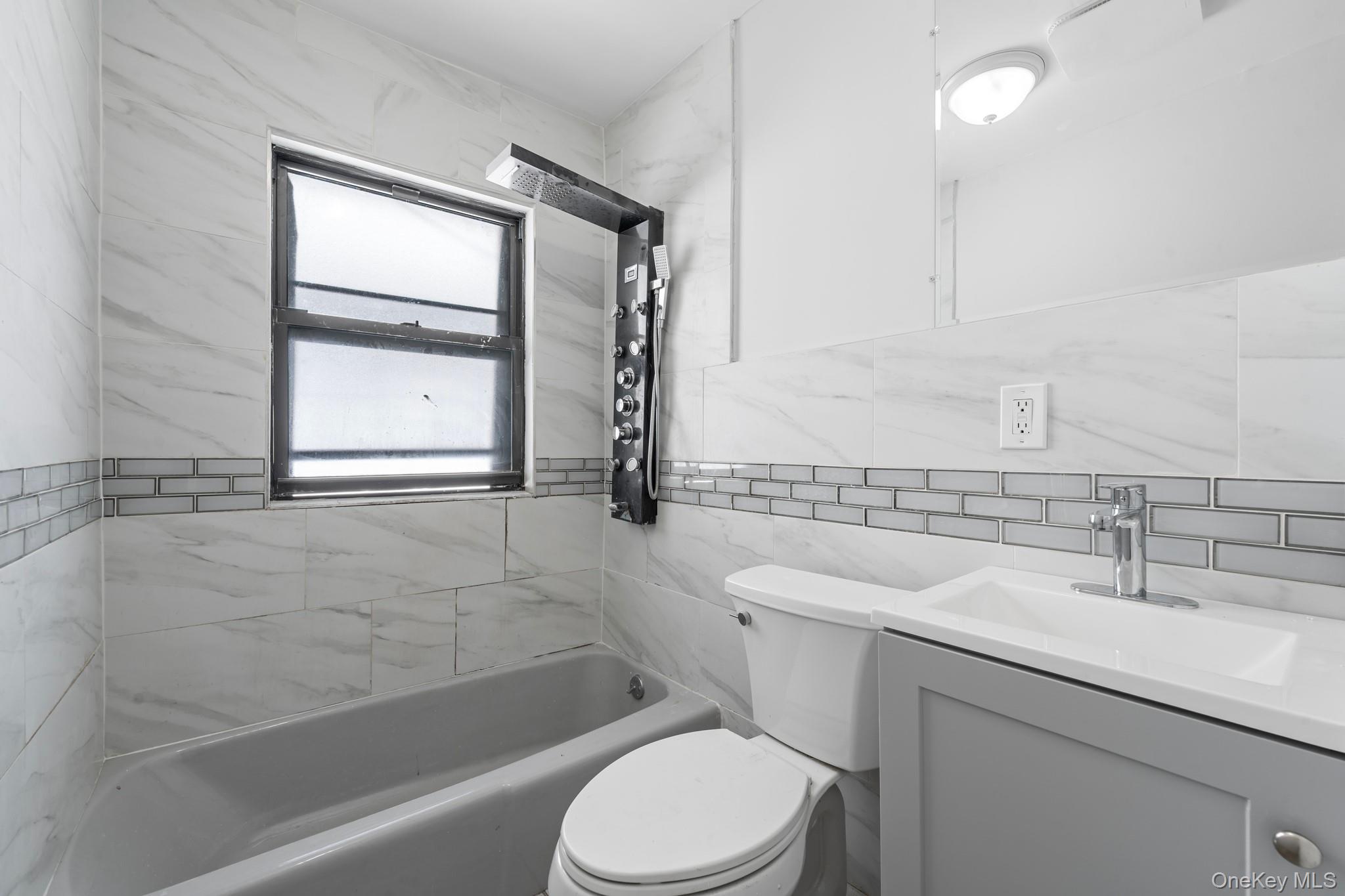 1069 East 35th Street Brooklyn, NY 11210 - Photo 10 of 16 Bathroom with vanity, shower / bath combination, and tile walls