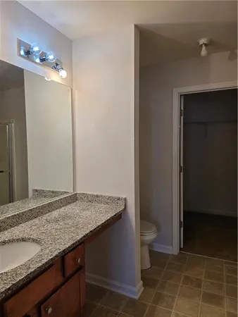 a bathroom with a granite countertop sink and a toilet