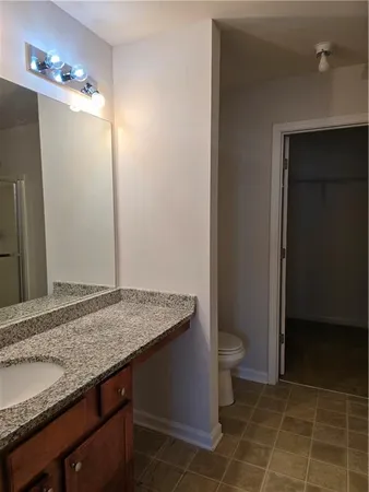 a bathroom with a granite countertop sink a toilet a mirror and shower