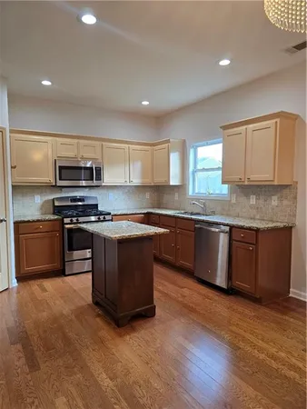 a large kitchen with stainless steel appliances granite countertop a stove a sink and a microwave