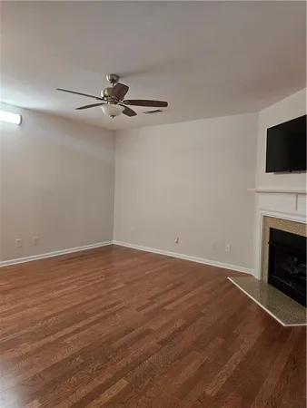 a view of an empty room with wooden floor fireplace and a window