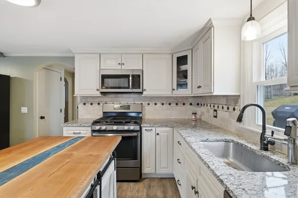 a kitchen with granite countertop a sink a stove and refrigerator