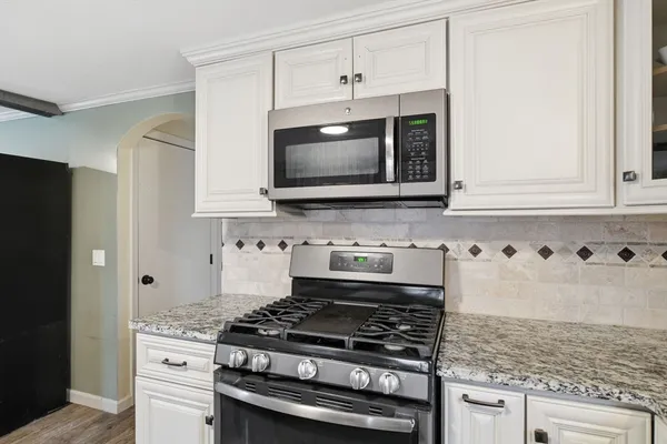 a kitchen with granite countertop a stove and a microwave