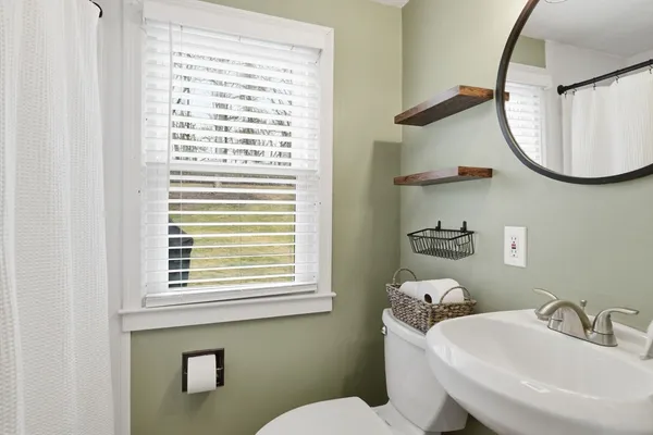 a bathroom with a sink a mirror a toilet and a window