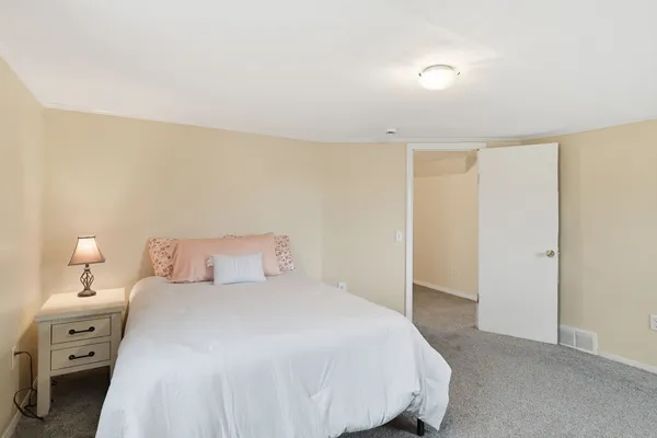 a spacious bedroom with a bed and a lamp