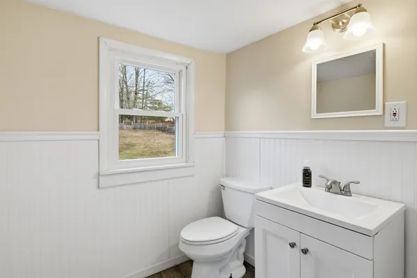 a bathroom with a toilet sink vanity and mirror