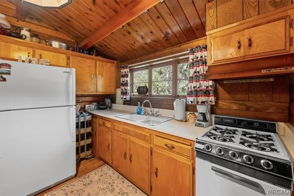 a kitchen with stainless steel appliances granite countertop a stove a refrigerator a sink dishwasher and white countertops with wooden floor